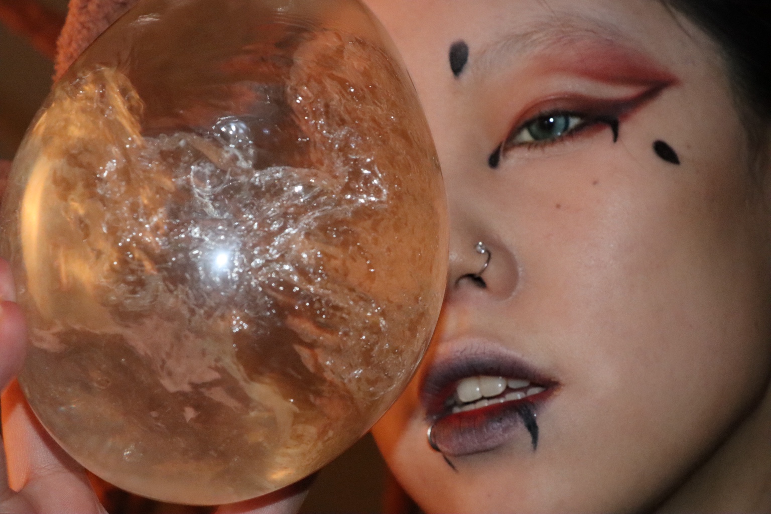 Close-up portrait with a transparent amber prop beside the face